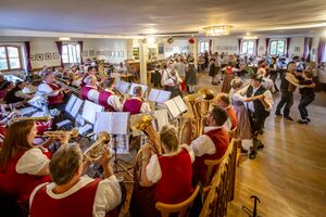 Musikgruppe mit tanzenden Menschen in Tracht in einem Wirtshaus am Zwiefachentag in Schwandorf 2024.