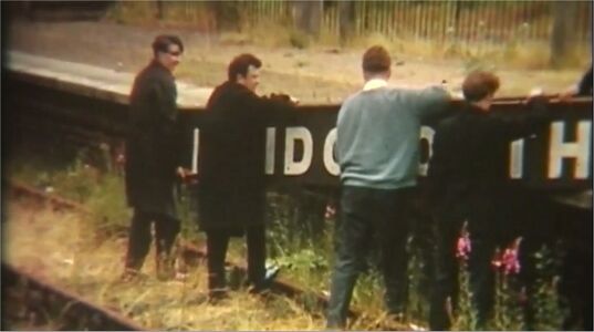 Society menbers lifting the station name board onto the platform